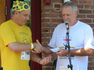 Jason "Jay" Scott accepts a ceremonial check from Mike Deneen, part owber of Union Street Tavern during the 7th Annual Tavern Trot in Windsor, CT.