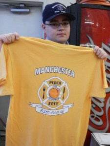 Dean Gates of the 8th Utilities Fire District shows t-shirts that were sold for the 65th Annual Peach Festival.