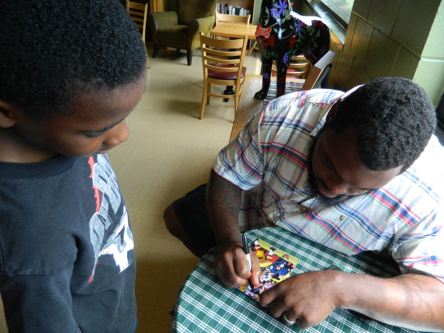 Chris Baker autographs a photo for Brendan Jenkins, 10, a student at Clover Street School in Windsor, CT where he plays football for the Windsor Giants.
