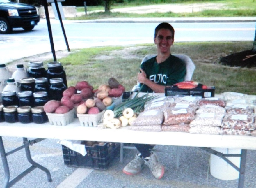 Andrew Comte mans a Farmers Market table.