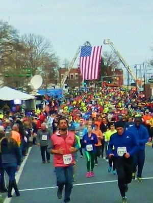 Runners pass under the American flag as they head for the 80th Manchester Road Race finish line. 